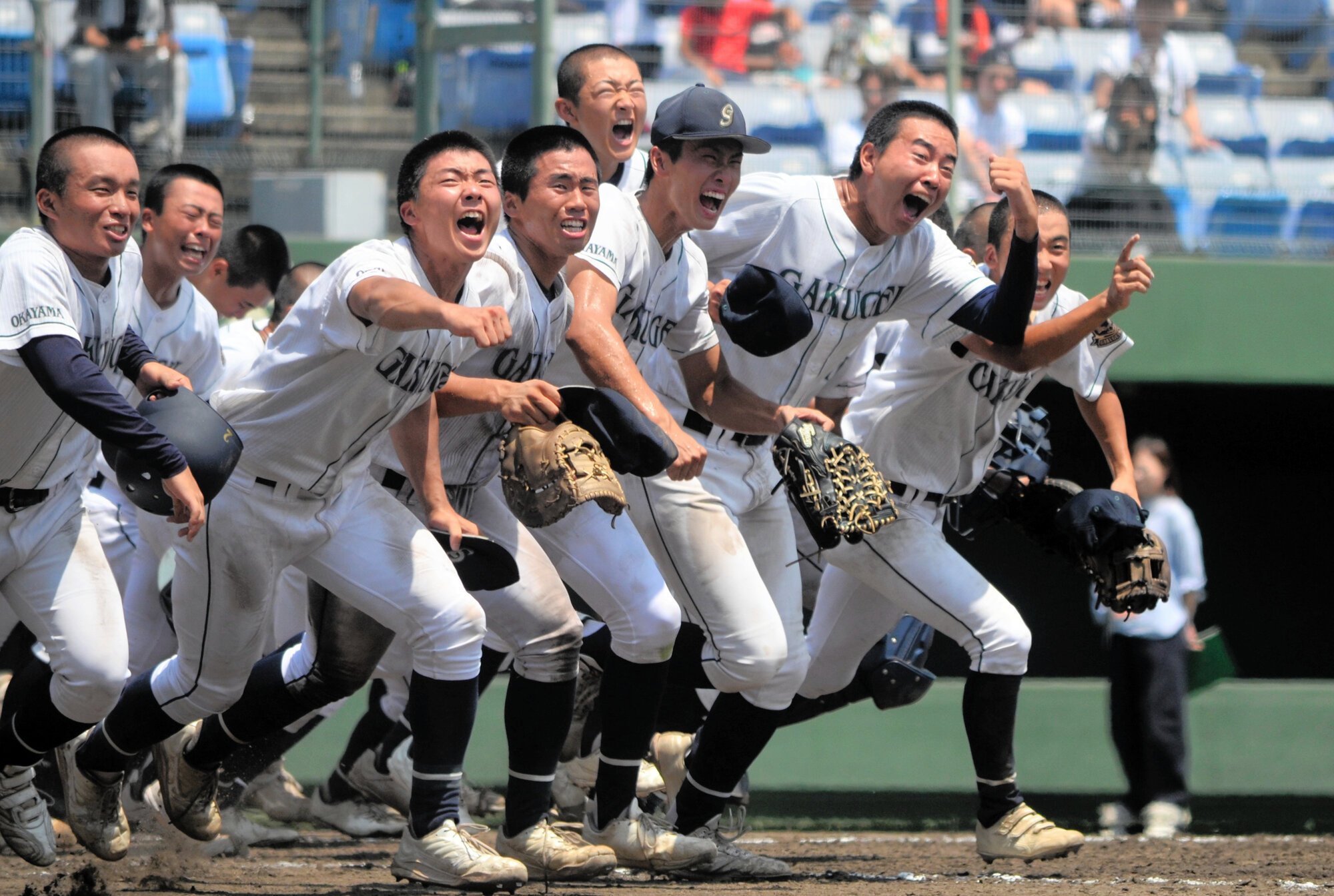 優勝を決めて校歌を歌い終え、応援してくれた人たちが待つ一塁側スタンドへ走り出す岡山学芸館の選手たち=2026年7月27日、マスカット、中川壮撮影