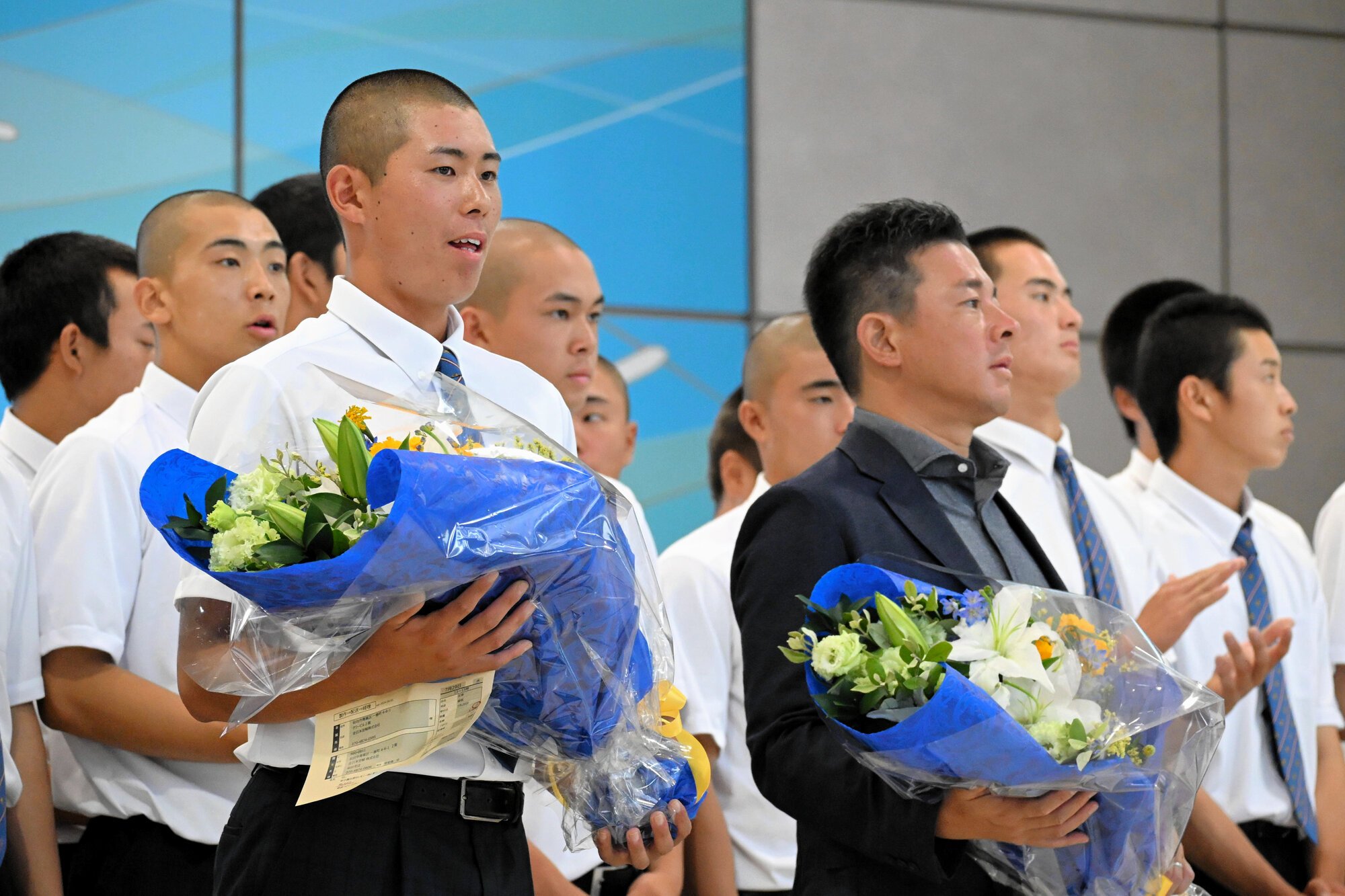 花束を受け取った仙台育英の倉田主将(左)と須江監督=2026年7月30日、仙台空港、三村悠撮影