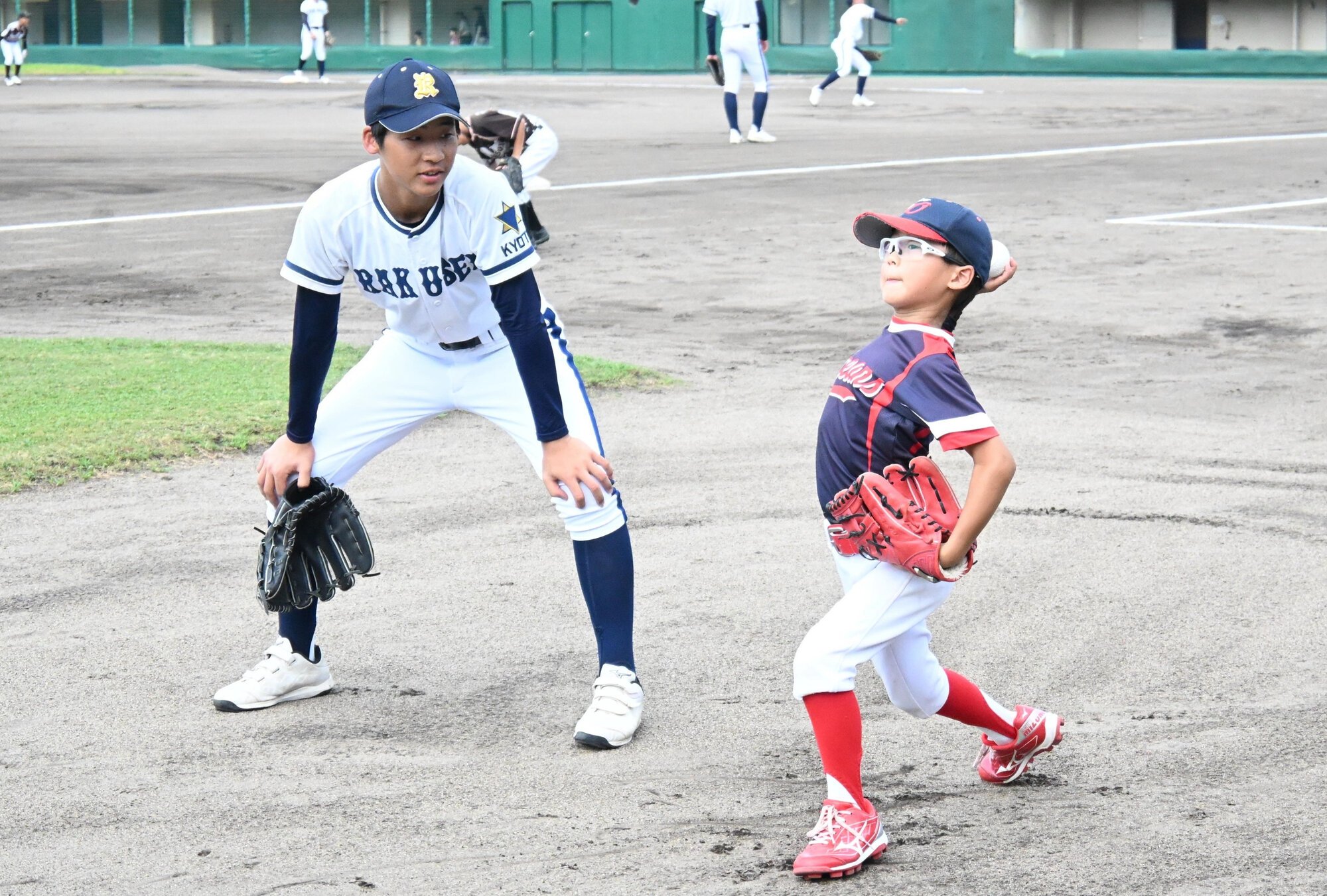 高校球児のアドバイスを受けてキャッチボールを体験する小学生=2026年7月30日午前10時10分、右京区のわかさスタジアム京都、城野怜於奈撮影