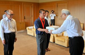 平屋隆之副知事(右)からボールを受け取る高川学園の衛藤諒大主将(中央)ら=2026年7月30日午後0時6分、山口県庁、松下秀雄撮影