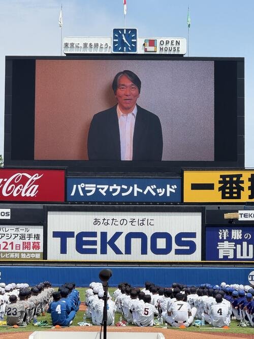 開会式で流れた松井秀喜さんからのビデオレターを、座りながら見入る選手たち(手前)