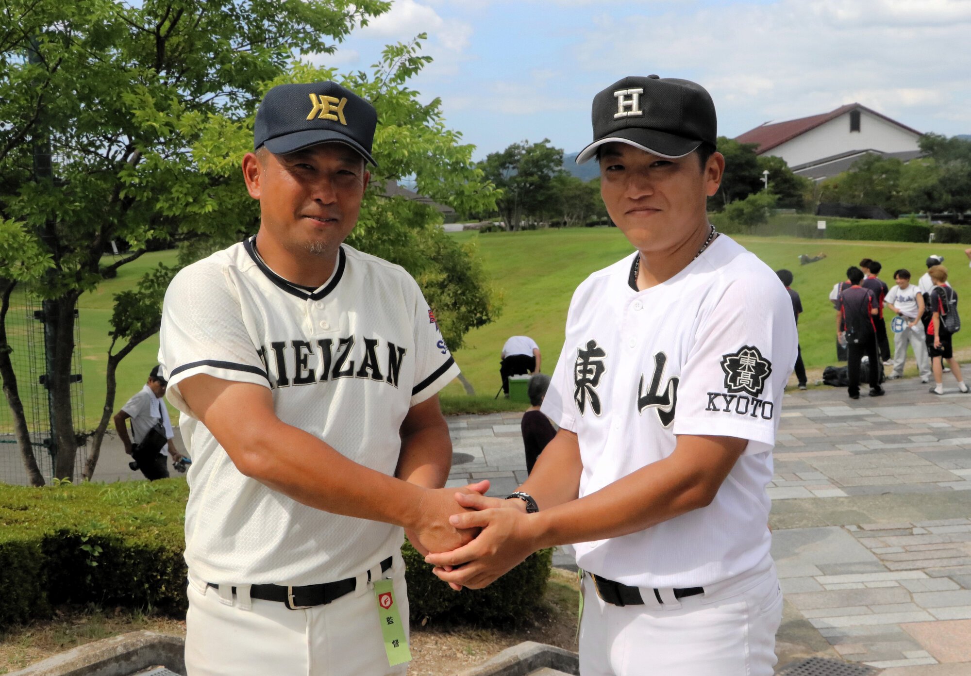 試合後、握手を交わす比叡山の西川弘基監督(左)と東山の山崎甫監督=2026年8月4日、京都府宇治市の太陽が丘球場、大野宏撮影