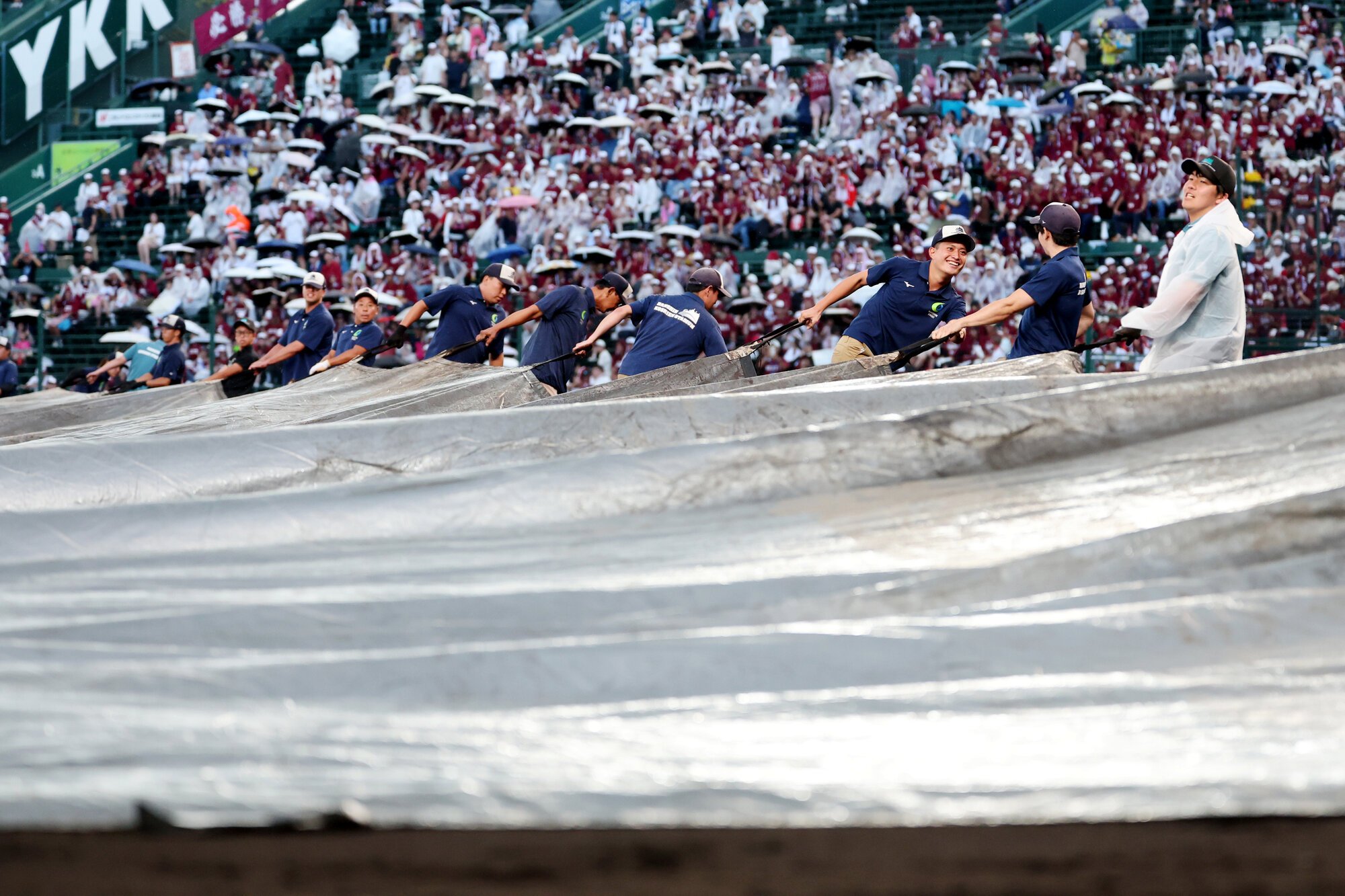 仙台育英―拓大紅陵　四回表の途中で雨天中断となり、グラウンドにシートをかける阪神園芸のスタッフたち＝内田光撮影
