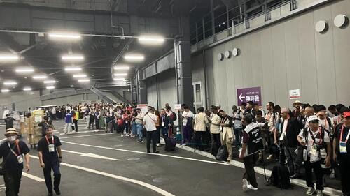 開会式後、シャトルバスの到着を待ちながら長蛇の列をつくる報道関係者たち