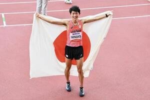 男子マラソンで優勝を決め日の丸を背に笑顔を見せる山下一貴(撮影･滝沢徹郎)