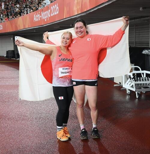 女子やり投げで準優勝の北口榛花(右)と銅メダルの武本紗栄は日の丸を背に記念撮影する(撮影･滝沢徹郎)