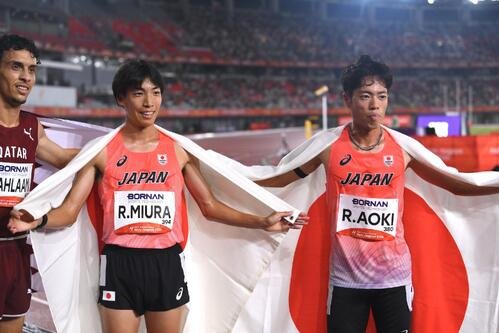 男子3000メートル障害決勝で優勝の三浦龍司(中央)は3位の青木涼真(右)と日の丸を背に記念撮影する(撮影･滝沢徹郎)