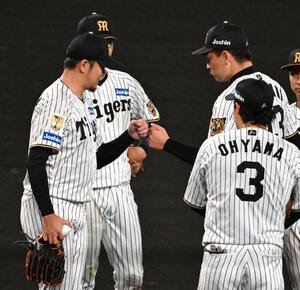 阪神対広島　7回表途中、降板する岩貞祐太(左)は岩崎優と拳を合わせる(撮影･石井愛子)
