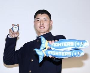 グッズを手に写真に納まる日本ハムから1位指名を受けた山梨学院･菰田陽生(撮影･河田真司)