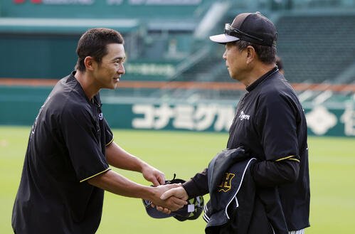 28日、練習前、熊谷敬宥(左)と握手を交わす阪神平田勝男新ヘッドコーチ
